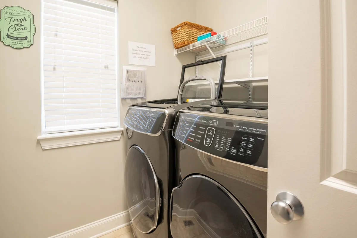 A well-organized laundry room with a modern washer and dryer, shelving, and baskets for organizing laundry needs. The space is clean and functional, brightened by efficient layout and storage.