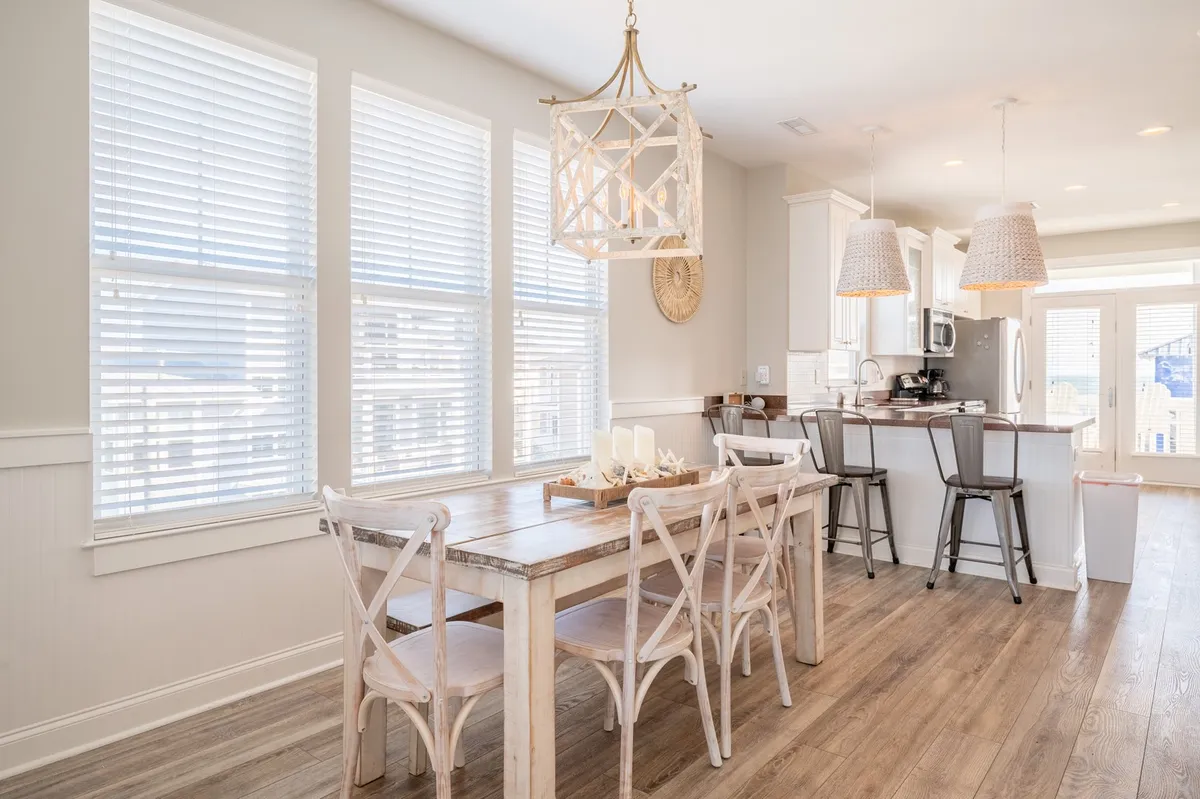 A cozy dining area centered around a French country dining table, illuminated by a decorative chandelier. Large windows flood the space with natural light, making it ideal for both everyday meals and festive gatherings.