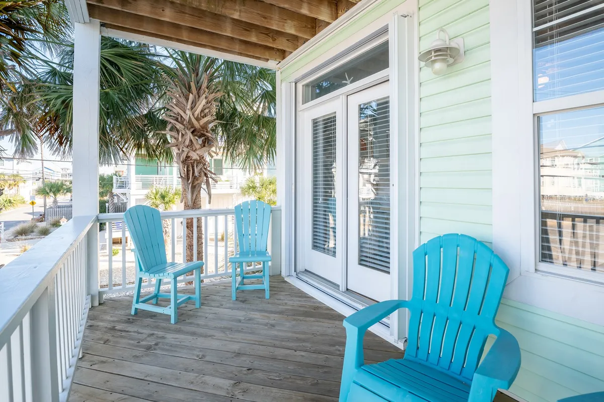 A relaxing wooden deck featuring turquoise chairs and palm trees, with a view that extends over water or lush surroundings. The mood is casual and welcoming, ideal for unwinding after outdoor adventures.